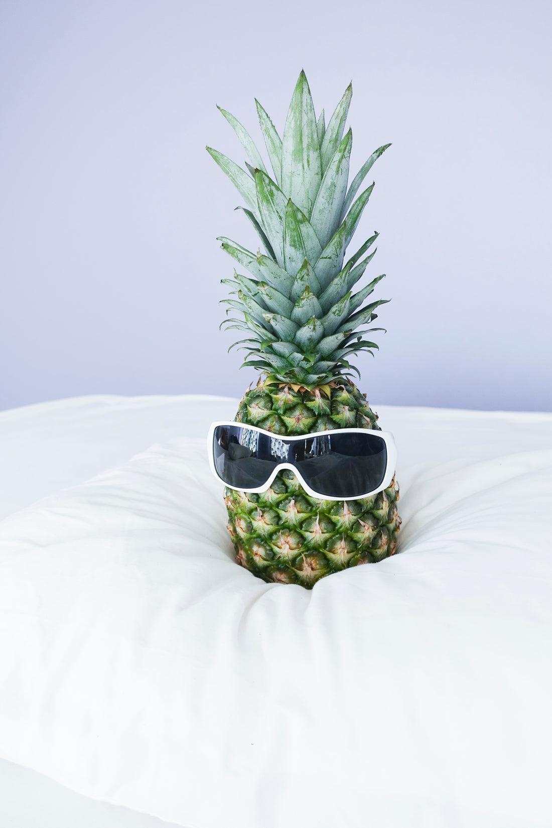 pineapple wearing sunglasses on bed